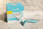 Gillette Venus Smooth refill blue box with Venus razor handle and white towel in bright morning sunlight on marble surface