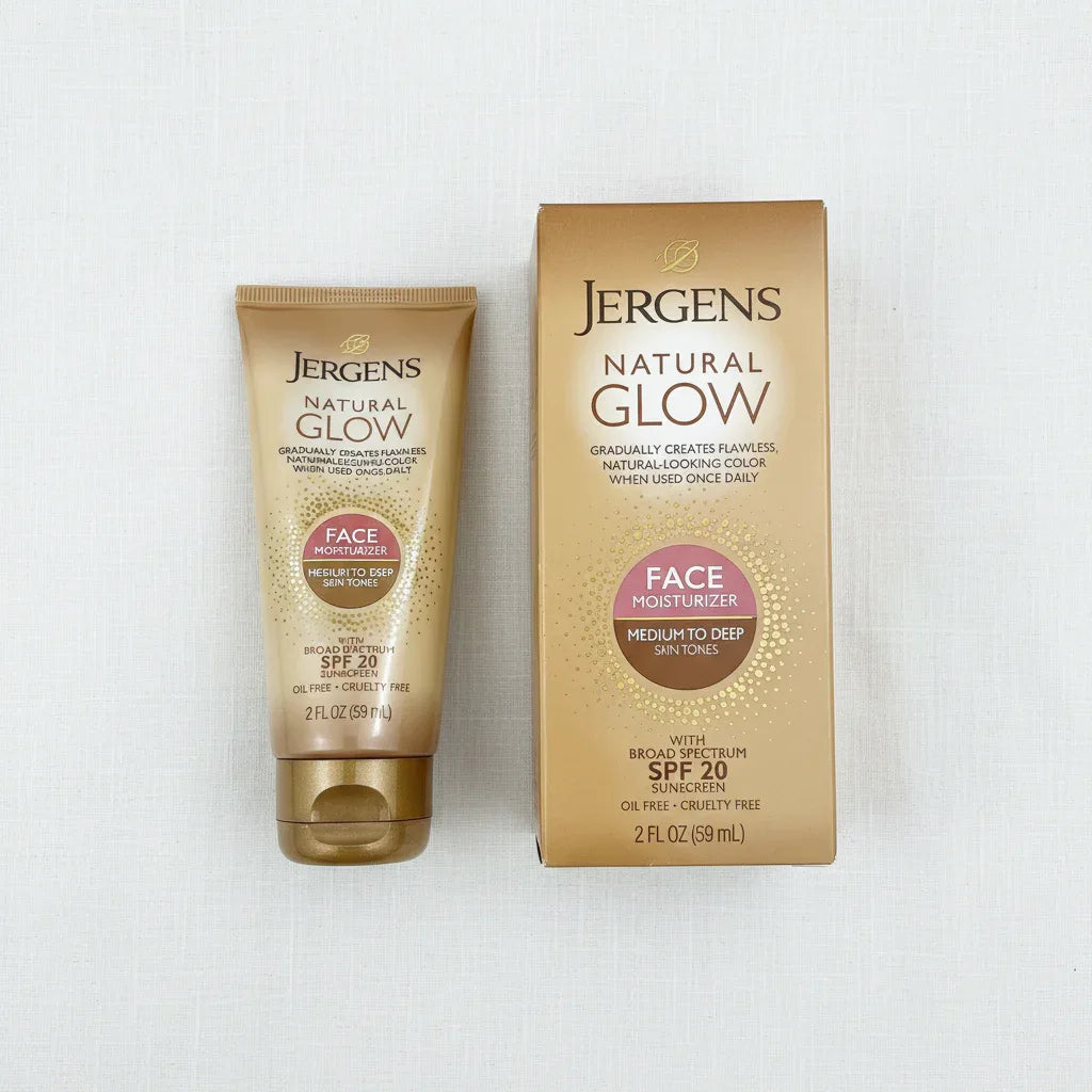 Overhead flat lay of Jergens Natural Glow gold face moisturizer tube and box on white linen surface, bright even lighting