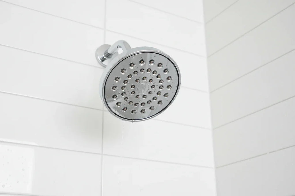 Professional interior photo showcasing polished chrome showerhead aesthetic bathroom hardware on white tile