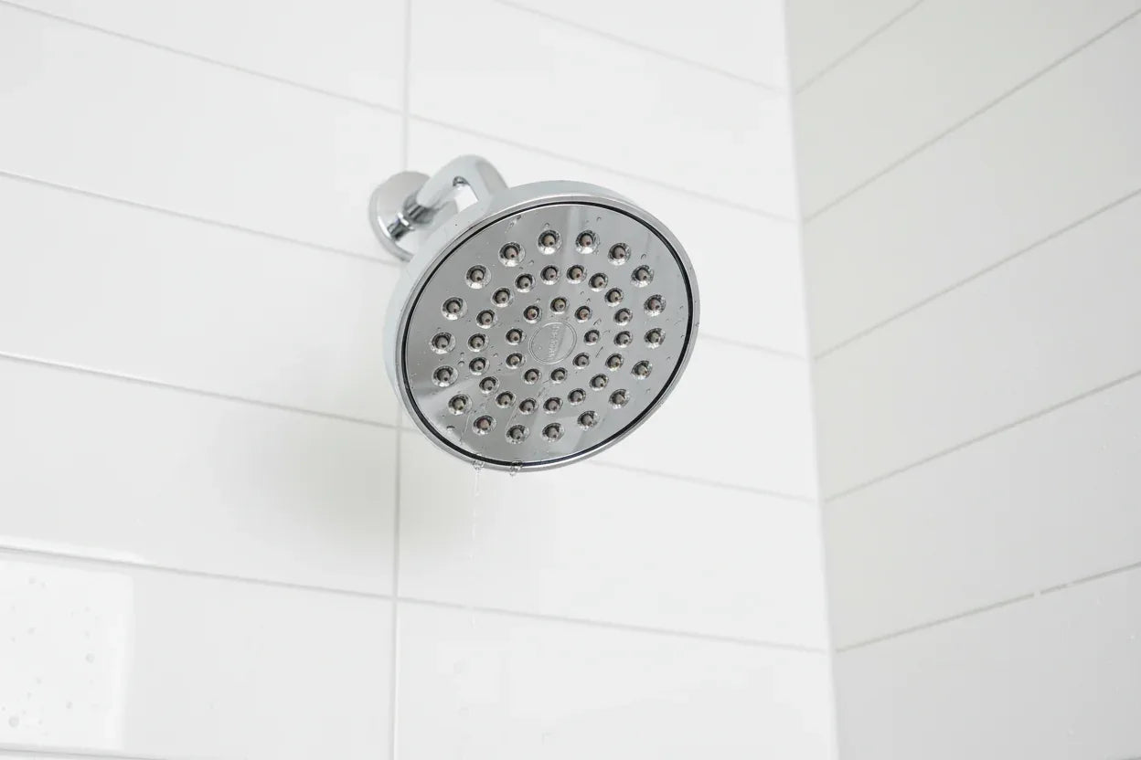 Professional interior photo showcasing polished chrome showerhead aesthetic bathroom hardware on white tile