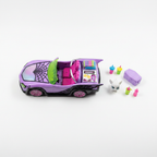 Overhead flat lay of the purple Monster High Ghoul Mobile toy car with ghost pet figure, coffin-shaped cooler, and drink accessories arranged on a white surface.