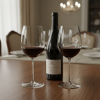 Pair of elegant flat-bottomed crystal red wine glasses filled with deep ruby Pinot Noir on a dark oak dining table beside a wine bottle