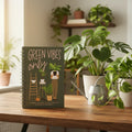 Green Vibes Only journal displayed on wooden desk next to live houseplants and watering can in natural home setting.