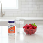 NOW Foods Chewable L-Theanine 100mg bottle on white quartz kitchen island with bowl of raspberries and clear glass of water