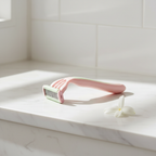 Women's razor resting on a minimalist white marble bathroom ledge with soft morning light