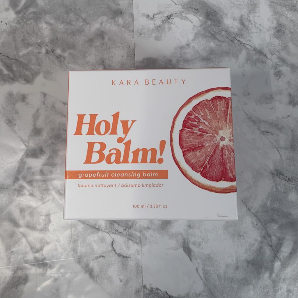 Kara Beauty Holy Balm grapefruit cleansing balm box on a simple neutral vanity surface