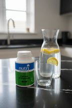 Nutri Advanced Calcium D-Glucarate bottle on black quartz kitchen counter next to lemon water carafe morning hydration station