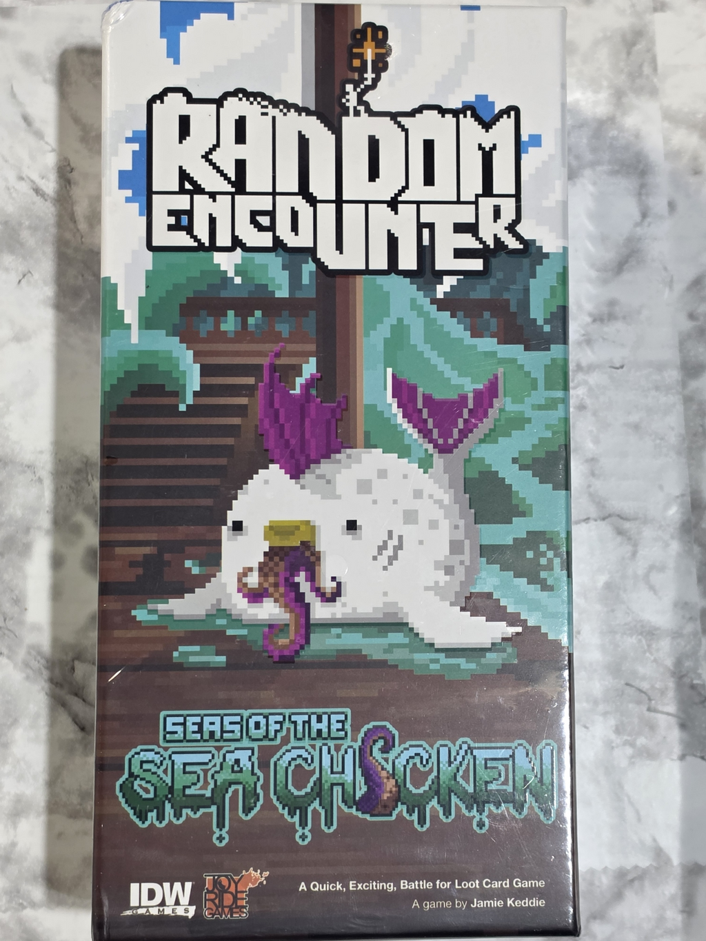 Card game box titled 'Random Encounter: Seas of the Sea Chicken' by IDW Games on a marble surface.