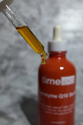 Close-up of a skincare dropper releasing a concentrated amber serum drop from a dark red-brown glass bottle in soft clean lighting