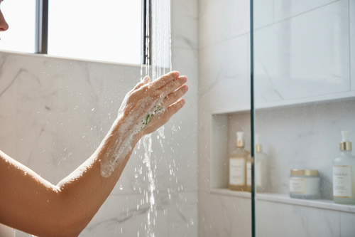 Woman exfoliating her smooth glowing arm in a bright shower, luxury body scrub lifestyle