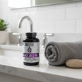 Zhou Black Seed Oil bottle on white quartz bathroom vanity shelf with rolled gray towel and decorative stone