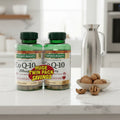 Nature's Bounty CoQ-10 200mg Twin Pack two green bottles on white quartz kitchen island next to metal water carafe and bowl of walnuts