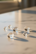 Clear serum droplets reflecting soft afternoon light on white marble vanity surface in warm soft natural lighting