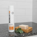BosleyMD Bos-Revive Conditioner on dark granite shower ledge with wooden soap dish and eucalyptus sprig