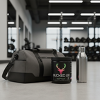 Bucked Up Original Strawberry Kiwi pre-workout container beside a gym bag and water bottle in a fitness studio