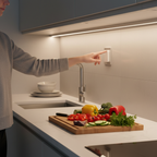 Person using wireless remote to control LED light bars above kitchen countertop