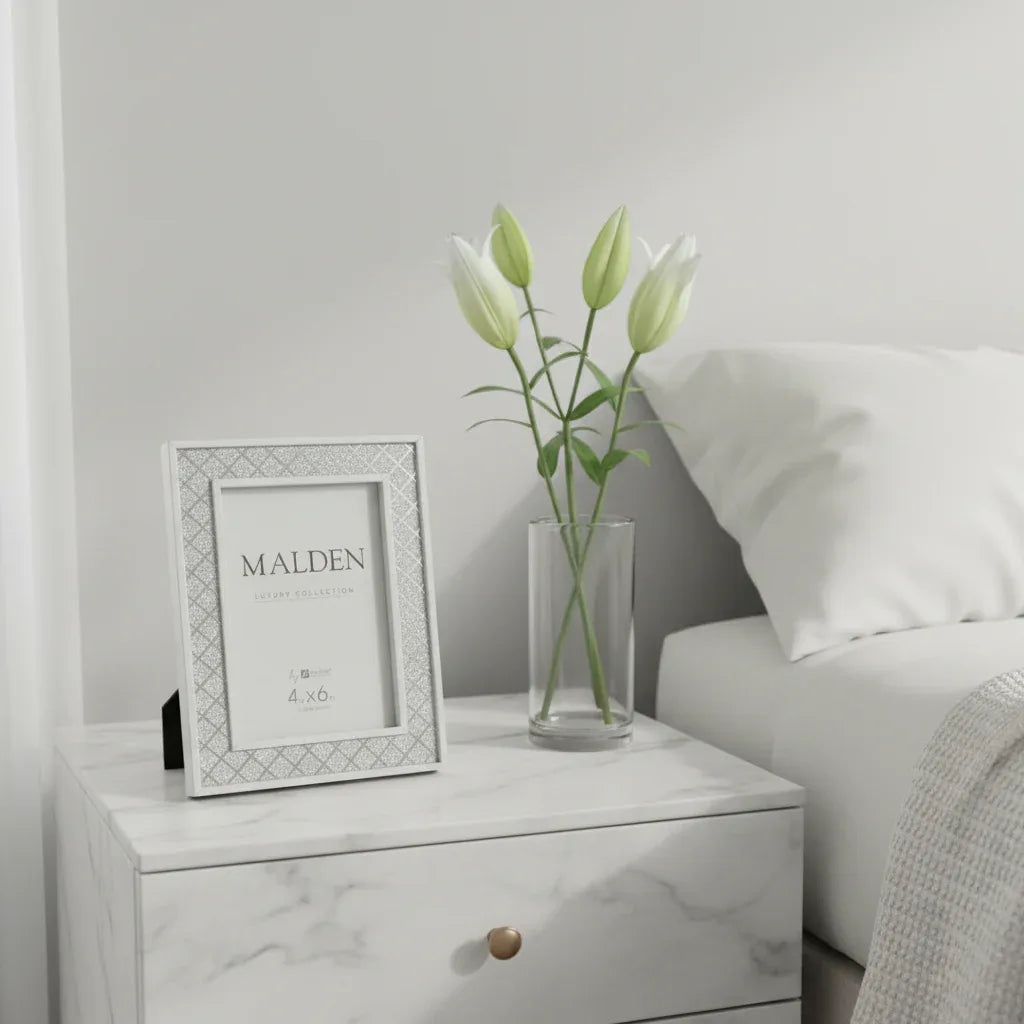 Malden silver glitter picture frame on minimalist bedroom nightstand beside white lilies, soft natural light