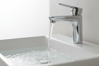 Water flowing from polished chrome single-handle faucet into sleek white washbasin