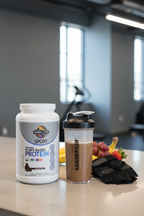 Garden of Life Sport Organic Plant Protein chocolate tub on gym counter with shaker bottle and fresh fruit