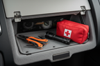 Orange handled stainless steel multi-tool in vehicle glove compartment with flashlight and first aid kit