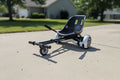 Hover-1 Buggy go-kart attachment connected to a self-balancing scooter on a sunlit outdoor concrete driveway