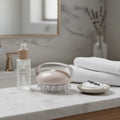 High-quality minimal skincare setup with ergonomic handheld body massage tool on white vanity marble surface