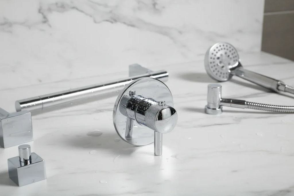 Close-up of sleek polished chrome bathroom trim hardware on a marble surface