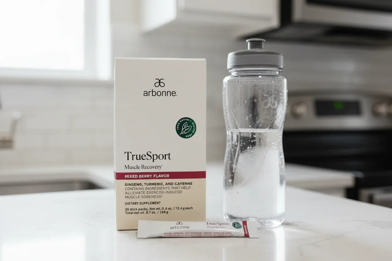 Arbonne TrueSport Muscle Recovery box on kitchen counter with water bottle and stick pack fitness lifestyle