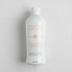 Overhead flat lay of elegant white aluminum health supplement bottle on white linen surface, bright even lighting