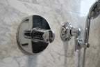 Close-up of polished chrome plumbing hardware with reflective depth on stone tile wall