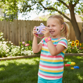Happy young girl holding Vivitar Kids Tech Kidzcam Camcorder purple panda edition recording video outdoors in sunny backyard
