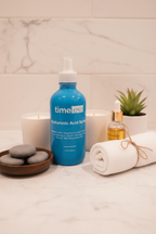 Organized high-end bathroom display featuring a large blue glass professional grade serum bottle with wellness products on white marble