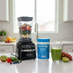 Vital Proteins Collagen Peptides tub next to blender with fresh fruits on kitchen counter for smoothie preparation.