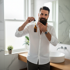 Well-groomed man applying beard oil to his full healthy beard in a bright modern bathroom