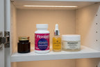 Florajen Women's Triple Action Probiotic 30ct bottle in white oak medicine cabinet with skincare jars — organized women's wellness supplement display