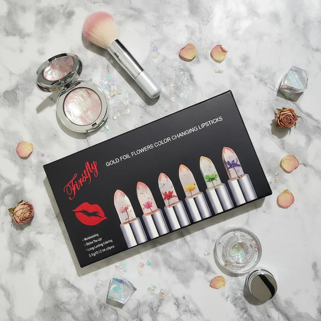 Flat lay of Firstfly Gold Foil Flowers lipstick array on white marble with decorative cosmetic tools