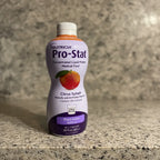 Nutricia Pro-Stat specialized clinical nutrition liquid protein bottle on natural stone surface, warm side lighting