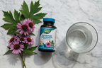 Dark amber supplement bottle next to fresh purple echinacea flowers and goldenseal leaves on marble