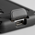 Close-up macro of black rugged phone case port cover open showing dust-blocking design detail