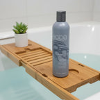 ABBA Moisture Conditioner 8 oz on bamboo bathtub caddy over porcelain bath with green succulent