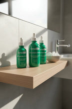 Professional bathroom shelf display with green glass skincare dropper bottles in soft morning light