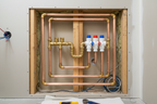 Close-up of professional pipe fitting work inside a bathroom wall cavity with brass fittings