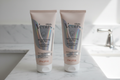Two Gillette Venus Skin Smoothing Exfoliant 6oz tubes side by side on white marble bathroom vanity in soft natural light
