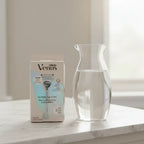 Gillette Venus Pubic Hair & Skin Razor Kit on white marble vanity top with glass carafe of water
