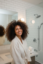 Woman with gorgeous voluminous natural curly hair smiling in bright modern bathroom after washing hair fresh lifestyle photo