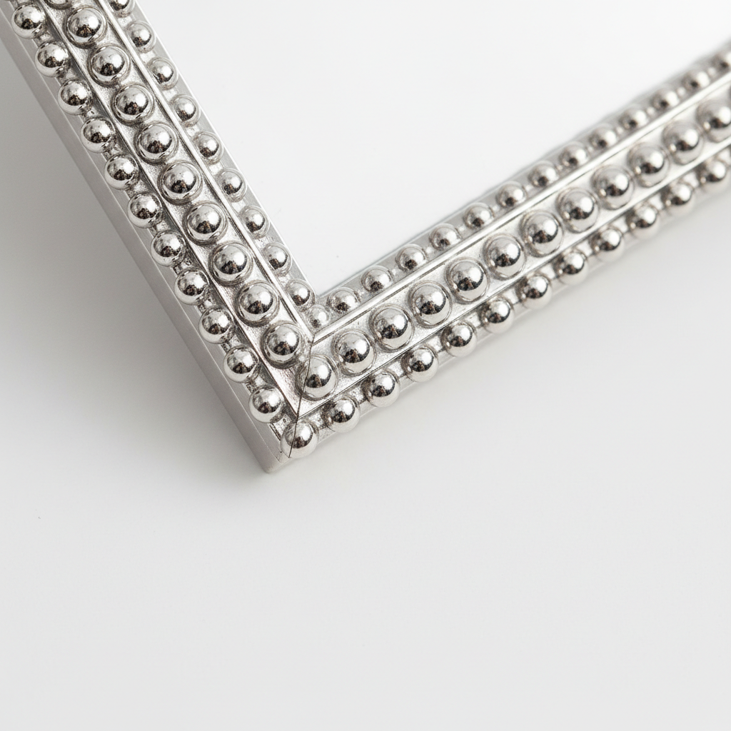 Close-up of an elegant silver-tone beaded picture frame detail on a white surface