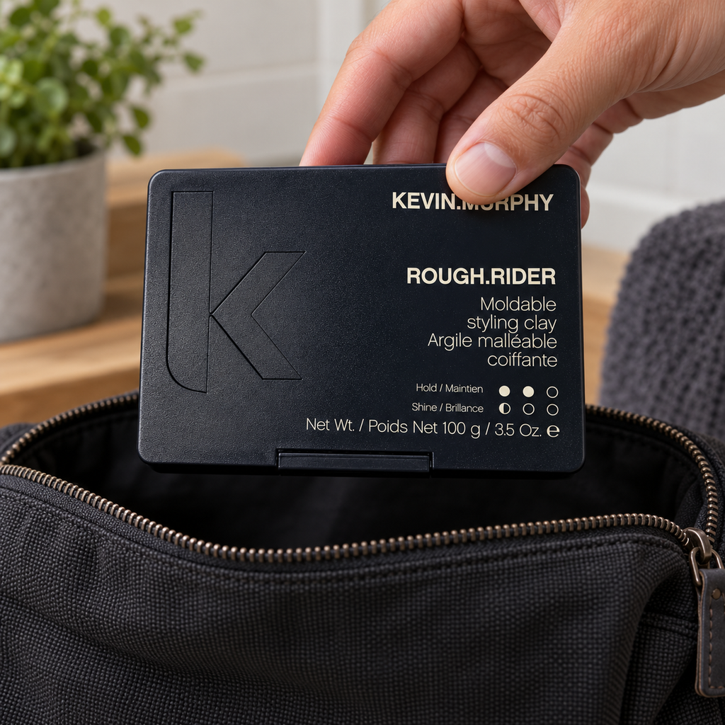 Hand placing a closed KEVIN.MURPHY ROUGH.RIDER 100 g case into an open toiletry bag.