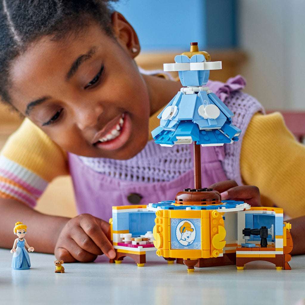 Child exploring the open display base of LEGO Cinderella’s Dress 43266 with Cinderella and Gus beside the model