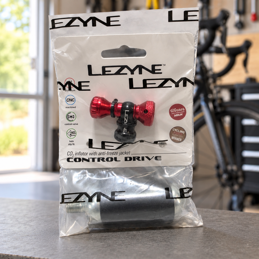 Red Lezyne Control Drive CO2 inflator with 16g cartridge in original package on a shelf in a cycling garage; AI-staged lifestyle composite.