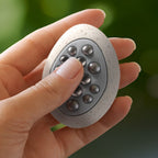Hand holding the Lifelines Pebbles Grounding Stone with its rolling ball bearings visible.